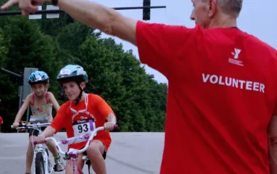 Adult Volunteer directing youth participants in a triathlon