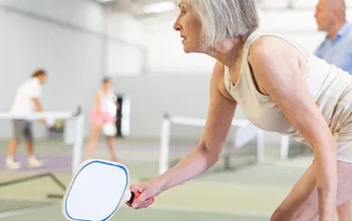 woman squatting for Pickleball on courts