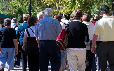 senior citizens on an outside tour walking with their backs turned