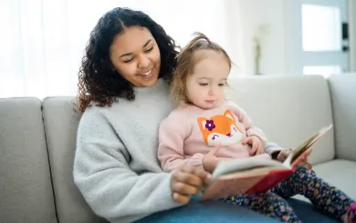 a teenage babysitter reads to a young child