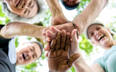 Image of active older adults smiling with hands in a circle