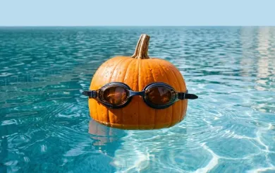 Pumpkin in swim goggles in pool water