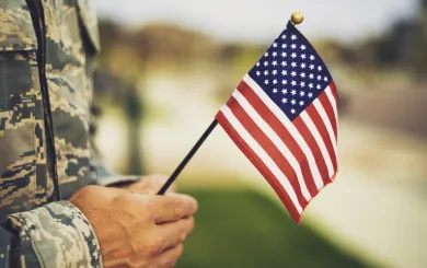 uniformed Military personnel holding a small American flag