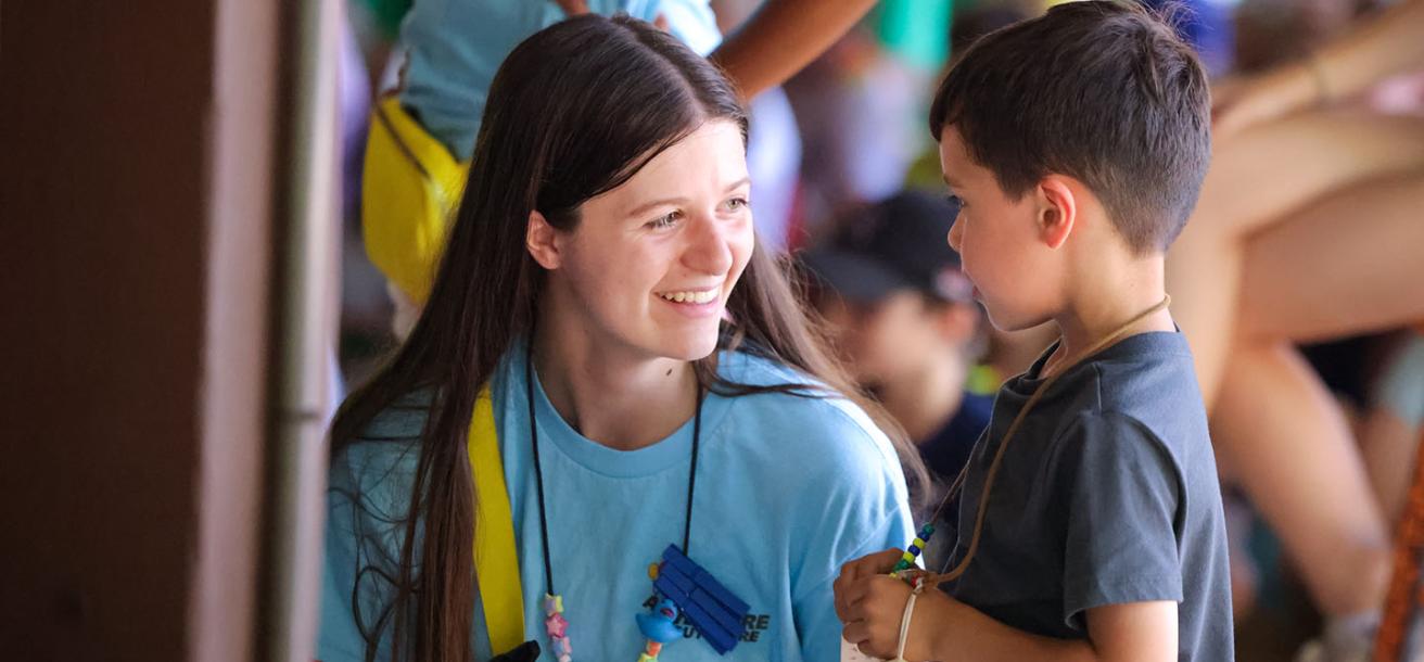 Counselor helping a child at camp