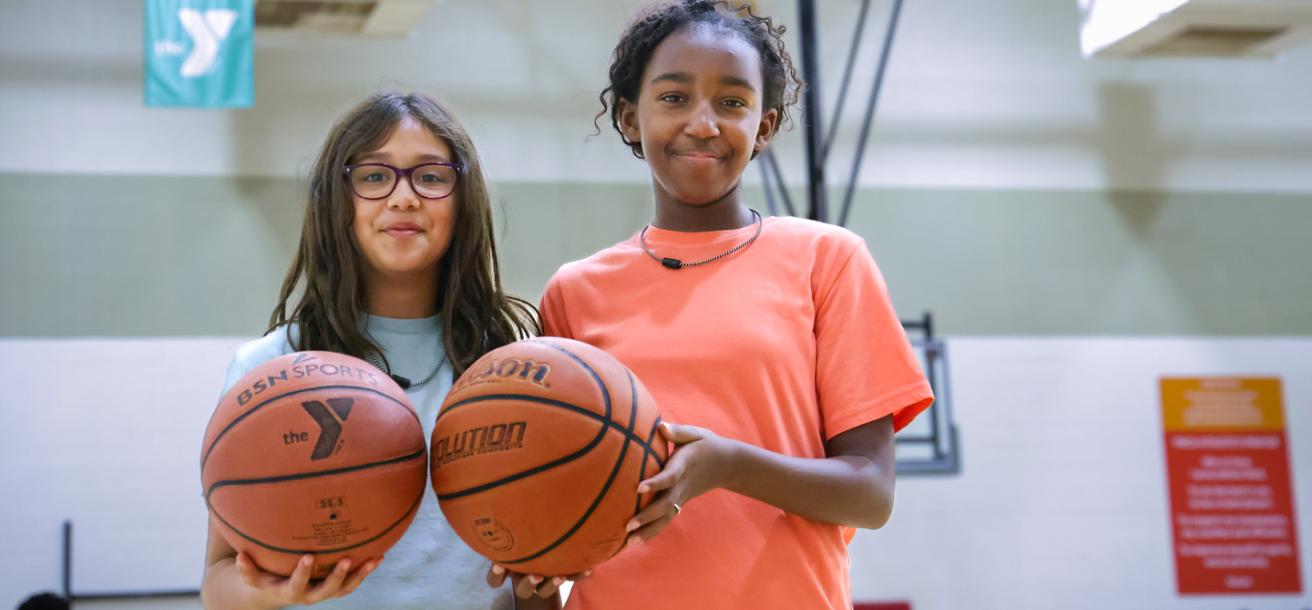 Two girls practicing basketball skills at day camp