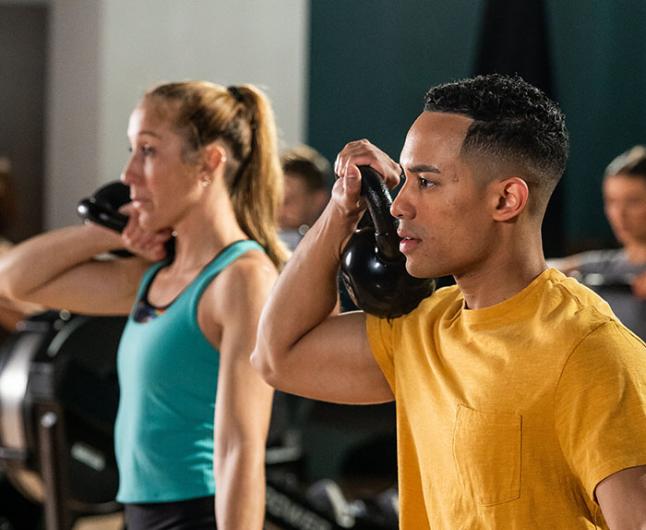Man and woman lifting kettle bells in a fitness class