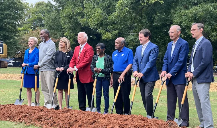 group of people holding shovels at the groundbreaking for the ymca youth center