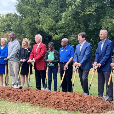 group of people holding shovels at the groundbreaking for the ymca youth center