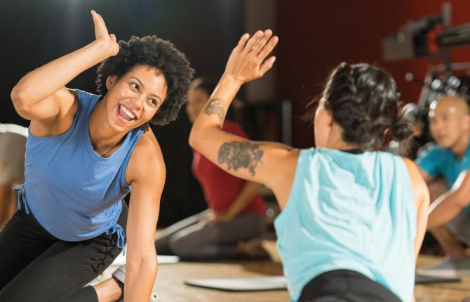 Two women in a group fitness class giving each other a high five.
