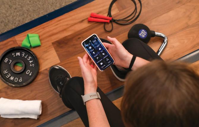 YMCA member holding a cell phone ready to use the new Member Pathways in the YMCA Fitness App