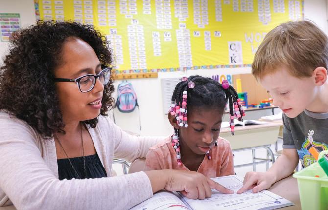 Teacher helping a child with reading skills