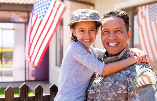 a military parent holds a child in front of American flag