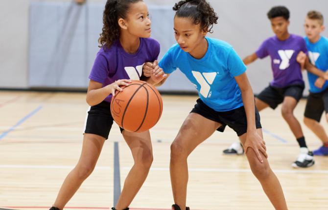 Two girls playing defense in youth basketball