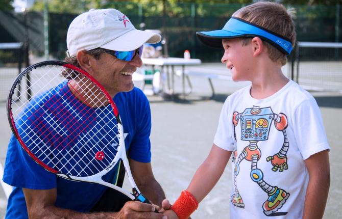 Coach helping a child with a tennis racquet