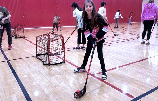 Girl learning the basics of street hockey at a clinic